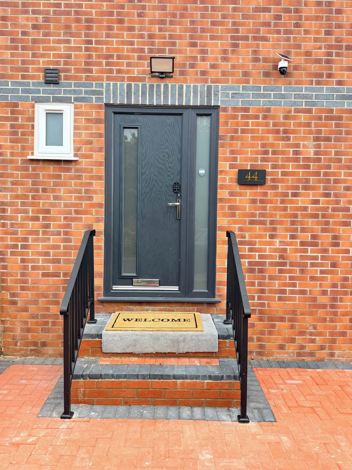 A brick building with a dark-colored door, a welcome mat, and a mailbox.