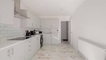 A modern kitchen with white cabinetry, a built-in oven, and a marble-patterned floor.