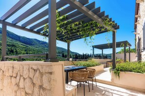 Une terrasse extérieure dotée d’une pergola, d’un espace salon et offrant une vue sur un paysage montagneux.