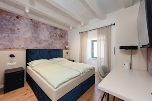 Une chambre à coucher avec un lit, une table de chevet, une lampe et une vue sur l’extérieur.