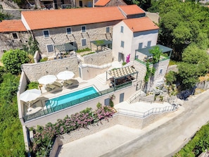 Un immeuble à plusieurs étages doté d’une piscine, d’un espace extérieur aménagé et d’une façade en pierre.