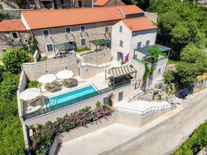 Un immeuble à plusieurs étages doté d’une piscine, d’un espace extérieur aménagé et d’une façade en pierre.