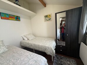 Un dormitorio con dos camas individuales, un armario y un espejo.