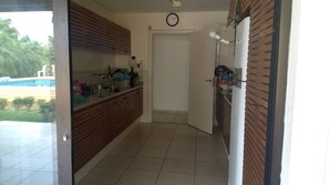 Cozinha com bancada de madeira, porta branca e vista para uma piscina externa.