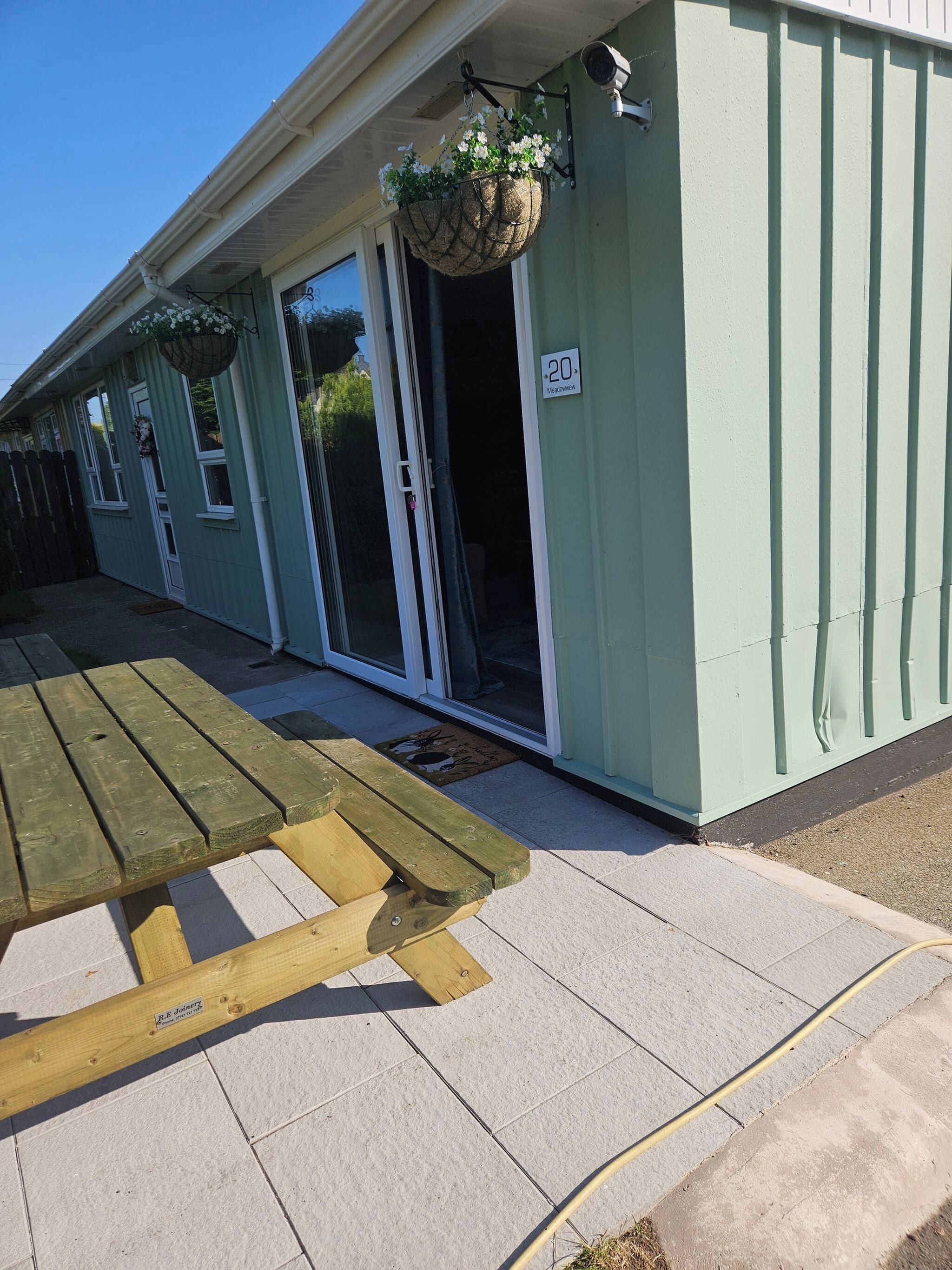 A building with a green exterior, a sliding glass door entrance, and a wooden bench outside.