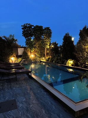 A swimming pool with lounge chairs and a tiled deck. - CosyNook apartments (Kigali)