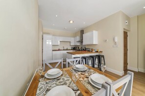 Une cuisine moderne avec des armoires blanches, un plan de travail en bois et un four encastré.