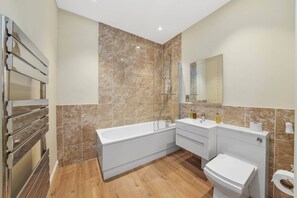 Une salle de bain moderne équipée d’une baignoire, de toilettes et d’une douche.