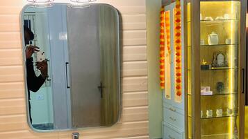 Un baño con un espejo grande, un lavabo redondo y un mueble de tocador con un gabinete de madera.