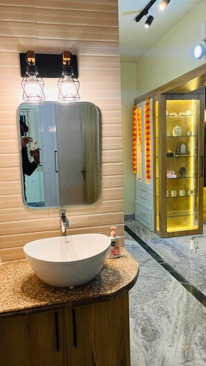 Un baño con un espejo grande, un lavabo redondo y un mueble de tocador con un gabinete de madera.