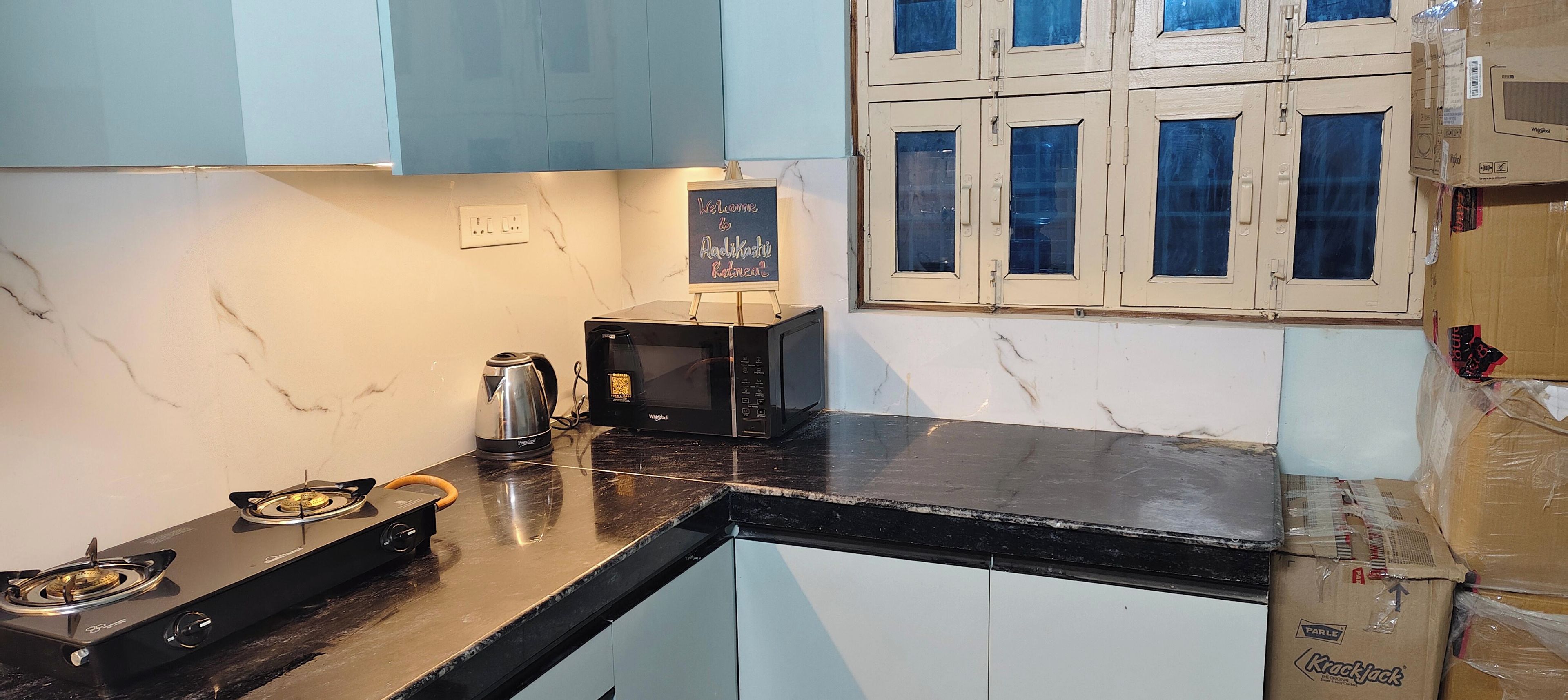 Una cocina compacta con estufa a gas, cafetera, microondas y armarios.