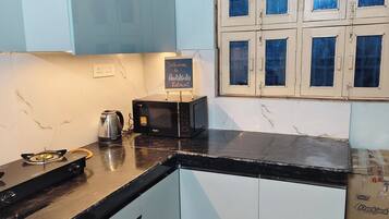 Una cocina compacta con estufa a gas, cafetera, microondas y armarios.