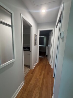 A hallway with wooden flooring, white walls, and doors leading to different rooms. - Escape the Ordinary! Unplug & Unwind on the best bridgeless Barrier Island in Fl (Placida)
