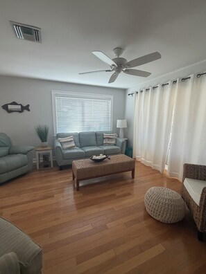 A living room with a sofa, a coffee table, a floor lamp, a ceiling fan, and a window with blinds. - Escape the Ordinary! Unplug & Unwind on the best bridgeless Barrier Island in Fl (Placida)