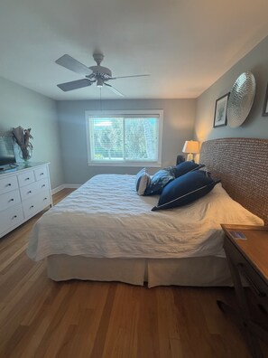 A bedroom with a bed, a ceiling fan, a window, a bedside table, and a dresser. - Escape the Ordinary! Unplug & Unwind on the best bridgeless Barrier Island in Fl (Placida)