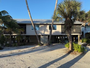 A two-story house with a covered patio, palm trees, and a gravel driveway. - Escape the Ordinary! Unplug & Unwind on the best bridgeless Barrier Island in Fl (Placida)