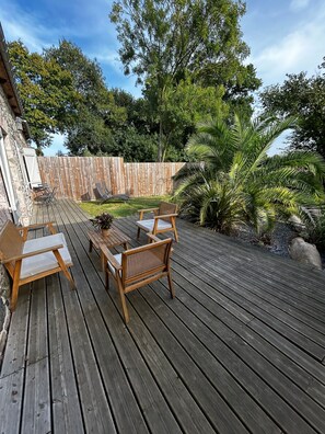 Eine Holzterrasse mit Gartenmöbeln, einer Steinmauer und einem Holzzaun.