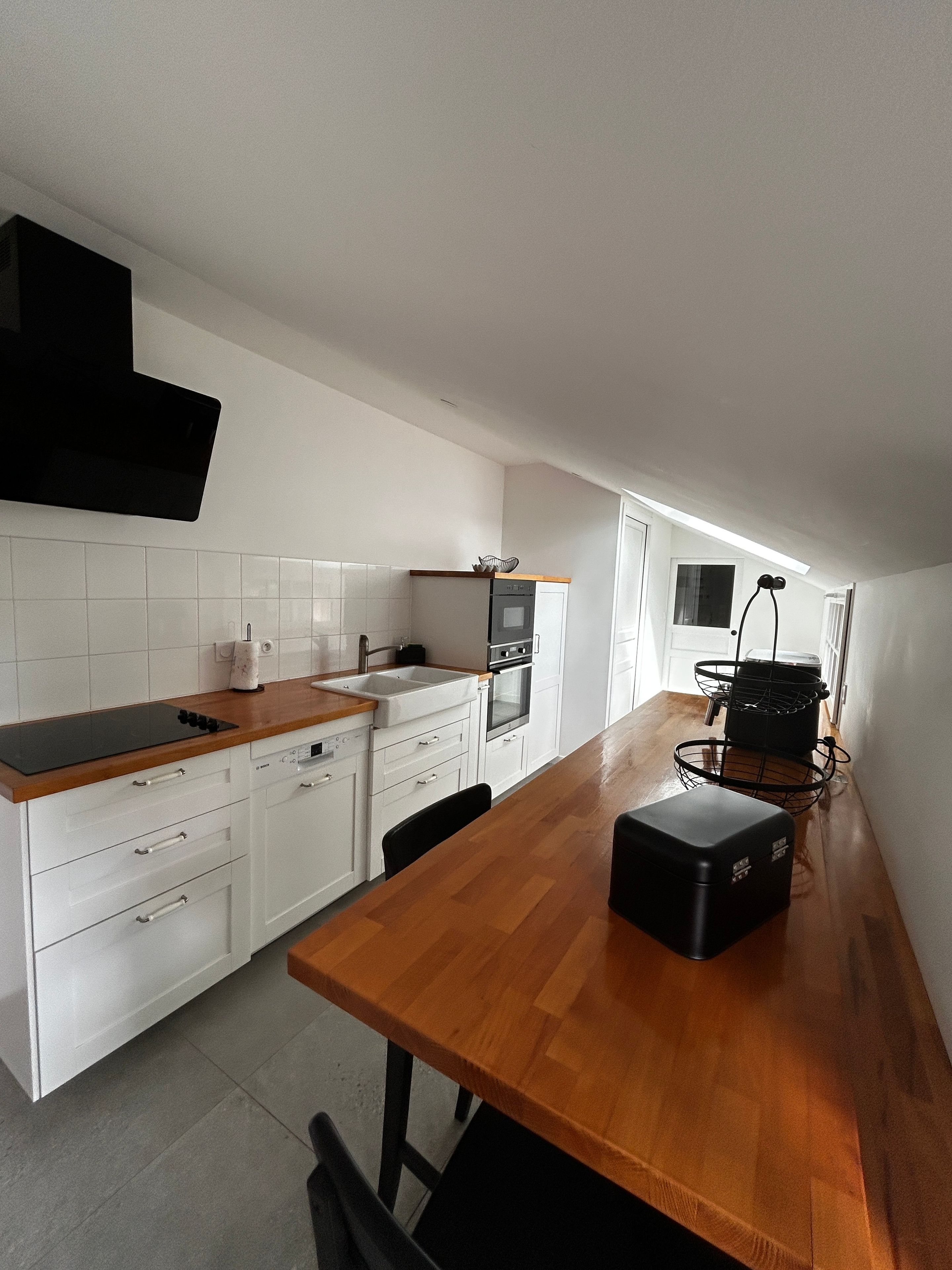 A modern kitchen with white cabinetry, a wooden countertop, and a built-in oven.