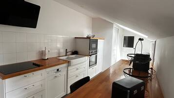 A modern kitchen with white cabinetry, a wooden countertop, and a built-in oven.
