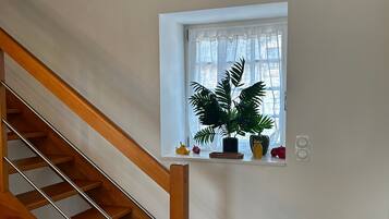 Een houten trap met een witte muur en een klein raam met een plant.