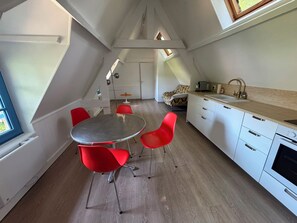 Une cuisine moderne avec un coin repas, comprenant une table ronde, des chaises rouges et un four encastré.