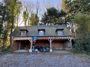 Une cabane rustique avec un panier de basket, un vélo et une terrasse en bois.