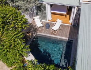Ein Pool auf dem Dach mit zwei Liegestühlen und einer Holzterrasse.