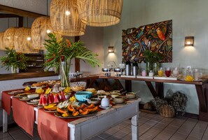 Tarjolla on monipuolinen buffet, seinälle on ripustettu koristeellinen taideteos ja nurkassa on kahvipiste.