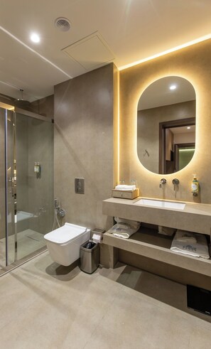 A modern bathroom with a glass-enclosed shower, a toilet, and a vanity with a mirror. - The Stone Hotel (Baku)