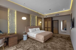 A modern bedroom with a large bed, a desk, and a chair. - The Stone Hotel (Baku)