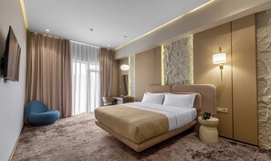 A hotel room with a bed, a chair, a desk, a lamp, and a wall-mounted phone. - The Stone Hotel (Baku)