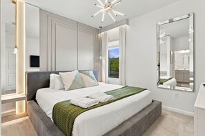 Un dormitorio moderno con una cama grande, un espejo y vistas al exterior.