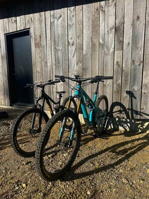 Twee fietsen geparkeerd voor een houten gebouw met een deur.