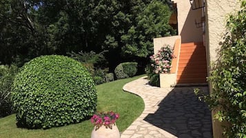 Un giardino curato con un sentiero in pietra che conduce a un edificio con facciata intonacata.