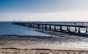 Eine Steg, der sich in ruhiges Wasser erstreckt, mit blauem Himmel darüber.