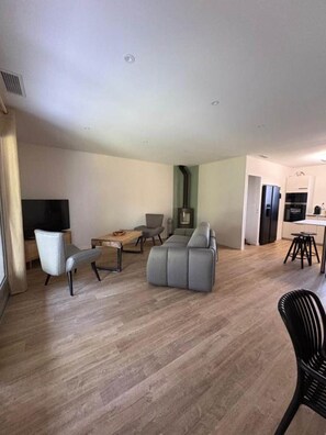 A modern living room with a grey sofa, a wooden coffee table, and a TV. - Vrbo Property (Andernos-les-Bains)