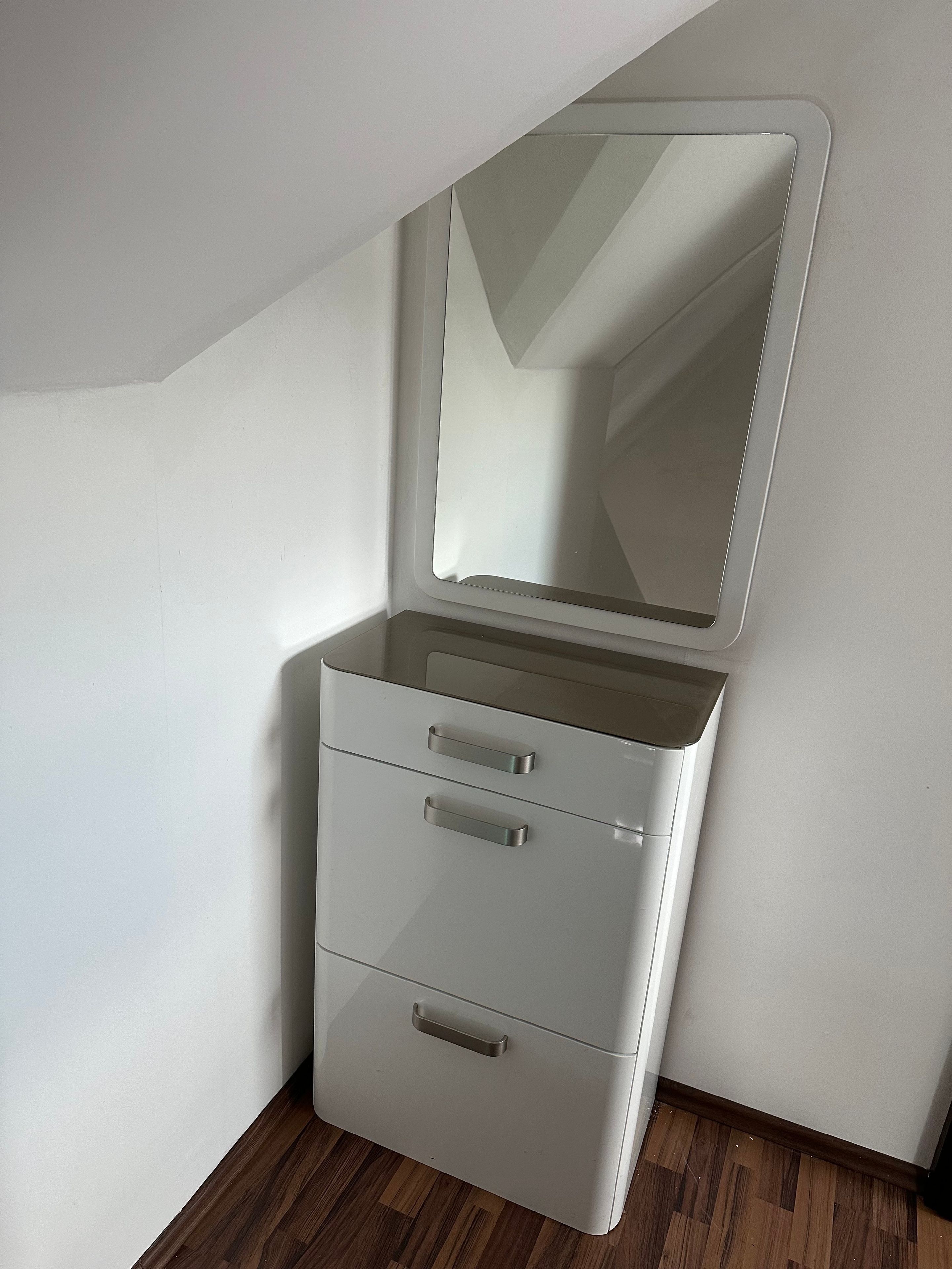 A white storage unit with drawers and a mirror.