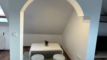 A modern interior with a white arched ceiling, a small table with a green plant, and two grey ottomans.