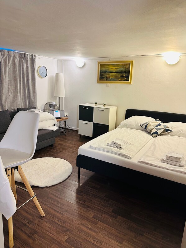 A modern bedroom with a bed, a chair, a desk, and a nightstand. - Apartment 'Souterrain Mit Privatem Parkplatz' with Wi-Fi (Graz)