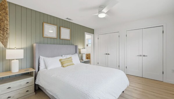 Ein Schlafzimmer mit Bett, Nachttischen, Deckenventilator und Kleiderschrank.