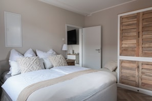 Une chambre à coucher avec un lit, des oreillers, une table de chevet, une lampe et une armoire en bois.