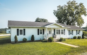 A single-story house with a front porch, a small front yard, and a large tree to the right. - Little Southern House at Southern Silos, Farmhouse getaway near Rolla, Missouri (Rolla)