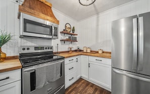 A kitchen with a stainless steel refrigerator, a microwave, an oven, and wooden countertops. - Little Southern House at Southern Silos, Farmhouse getaway near Rolla, Missouri (Rolla)