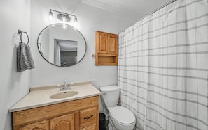 A bathroom with a wooden vanity, a round mirror, a toilet, and a shower curtain. - Little Southern House at Southern Silos, Farmhouse getaway near Rolla, Missouri (Rolla)