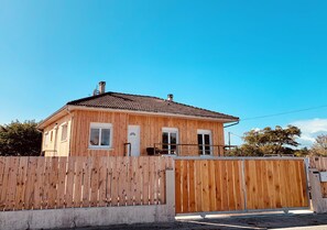 A single-story wooden house with a tiled roof, a wooden fence, and a clear blue sky. - New Listing (Le Verdon-sur-Mer)