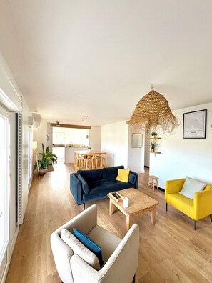 A modern living room with a sofa, armchair, coffee table, and a yellow armchair. There is a dining area with a table and chairs in the background. - New Listing (Le Verdon-sur-Mer)