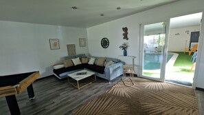 A living room with a sectional sofa, a coffee table, a pool, and a sliding glass door leading to an outdoor area. - New Listing (Troarn)