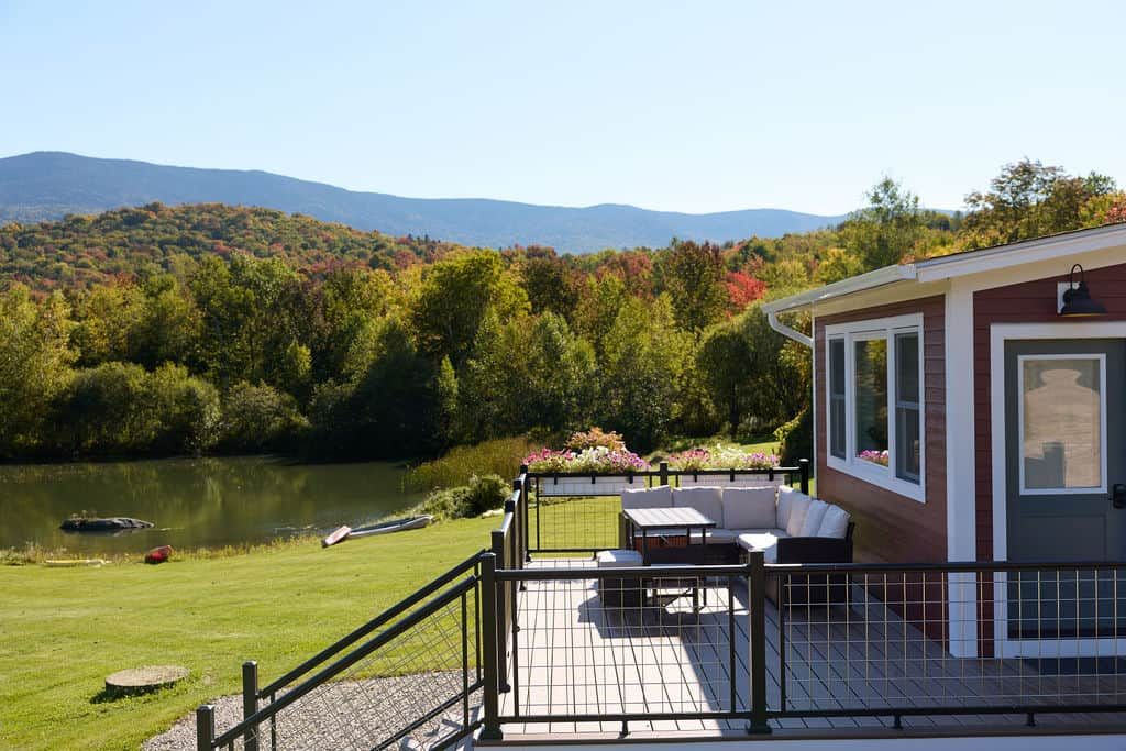 A deck with outdoor furniture overlooking a lake and forested hills.