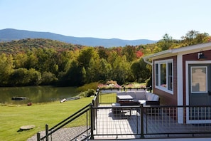 Une terrasse dotée de mobilier d’extérieur, offrant une vue sur un lac et des collines boisées.