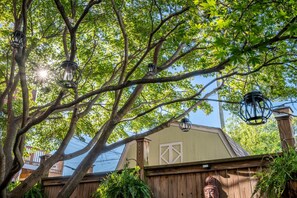 Une clôture en bois avec une structure ressemblant à une grange, un ciel dégagé et des lanternes suspendues.